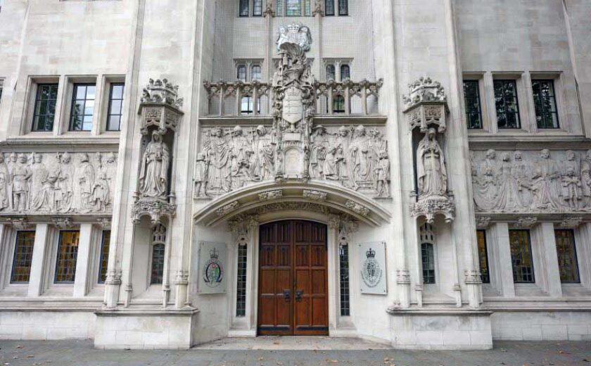 Ornate stone façade of Supreme Court building with large wooden doors