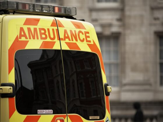 Rear of yellow ambulance with red chevrons and 'AMBULANCE' text