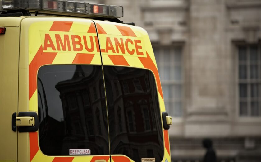 Rear of yellow ambulance with red chevrons and 'AMBULANCE' text