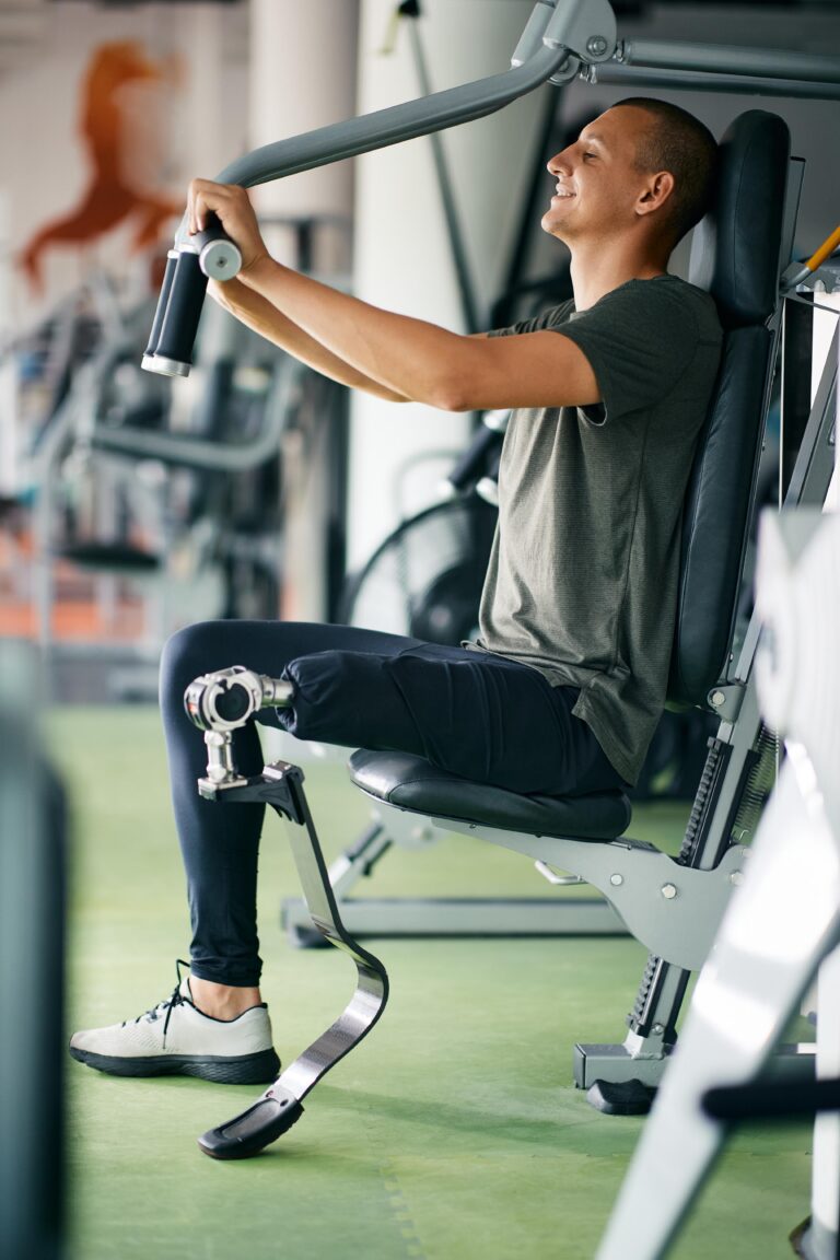 Happy amputee doing exercises for upper body strength on exercise machine at gym.