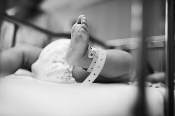 Newborn baby's foot with hospital identification band in crib