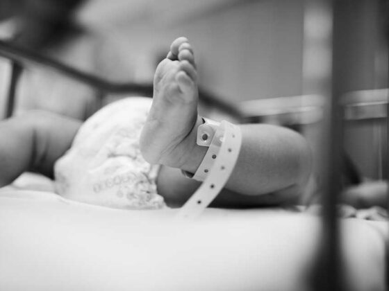 Newborn baby's foot with hospital identification band in crib
