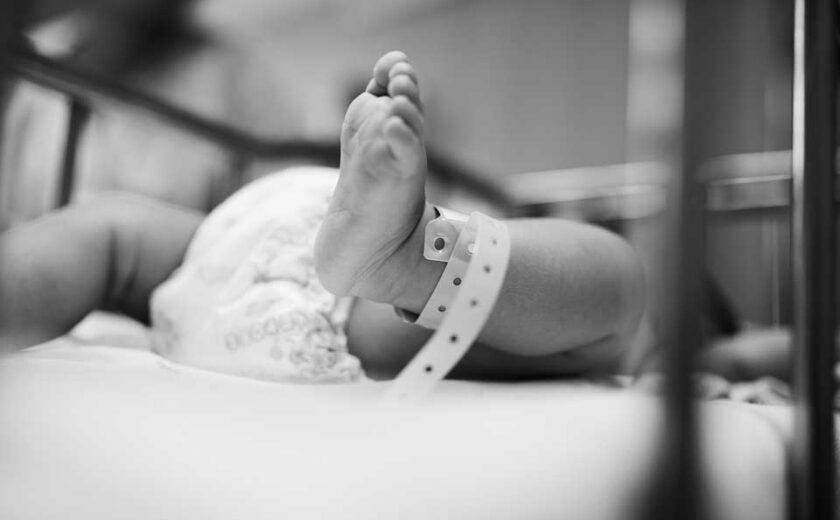 Newborn baby's foot with hospital identification band in crib