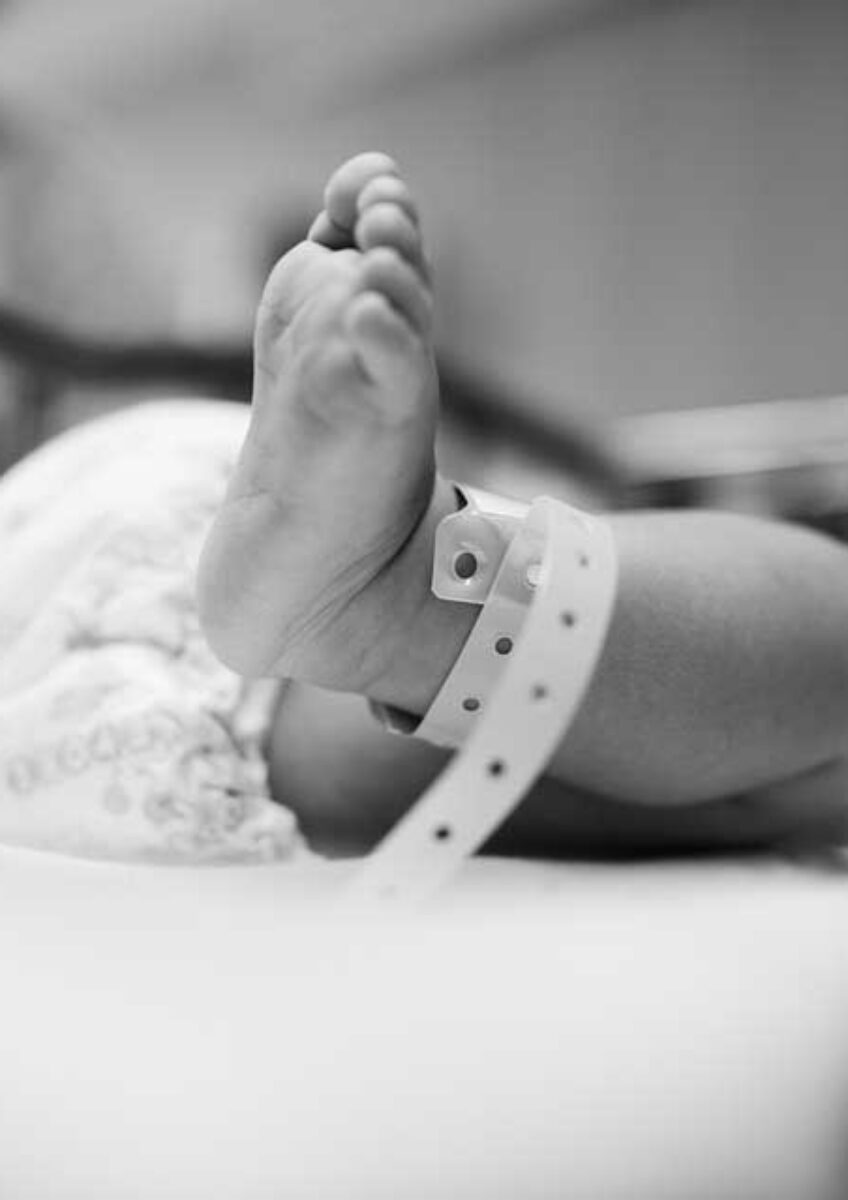 Newborn baby's foot with hospital identification band in crib