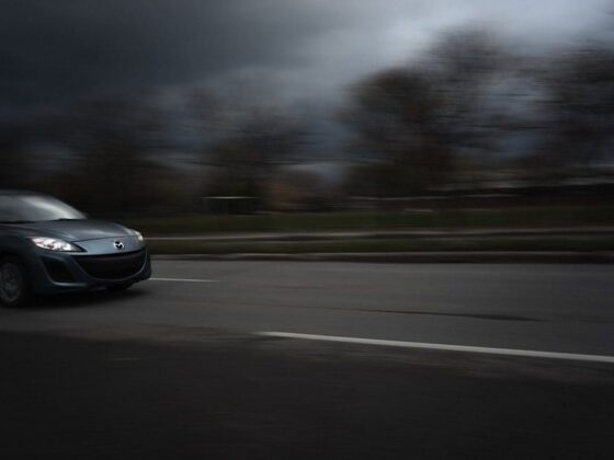 Dark car driving quickly on a road with blurred motion effect