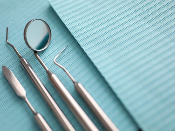 Four stainless steel dental examination tools on a blue dental bib