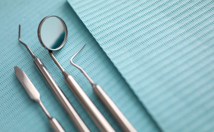 Four stainless steel dental examination tools on a blue dental bib