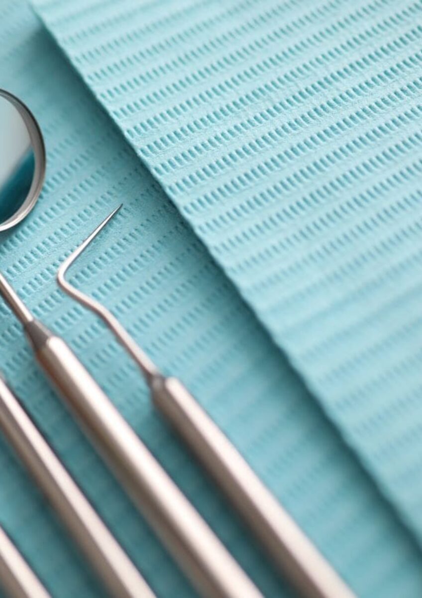 Four stainless steel dental examination tools on a blue dental bib