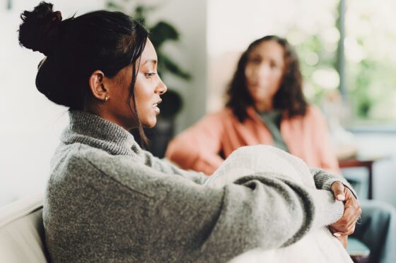 Young woman wrapped in blanket in therapy session with another woman