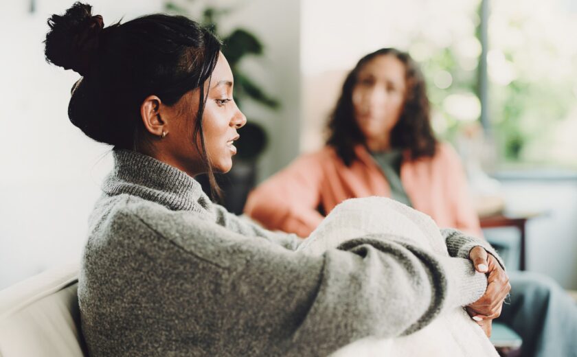 Young woman wrapped in blanket in therapy session with another woman