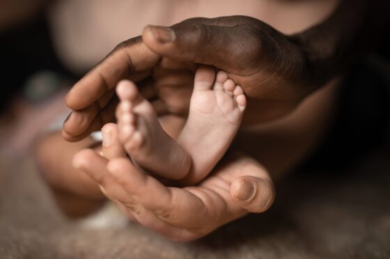 Hands of two adults gently holding a baby's feet