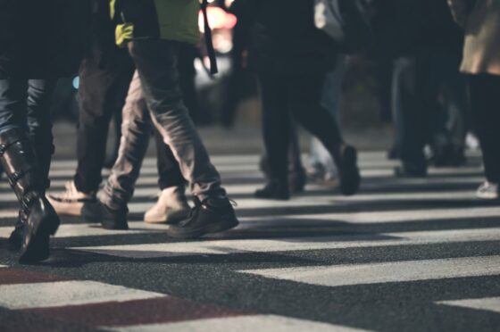 Various people crossing a zebra crossing at night