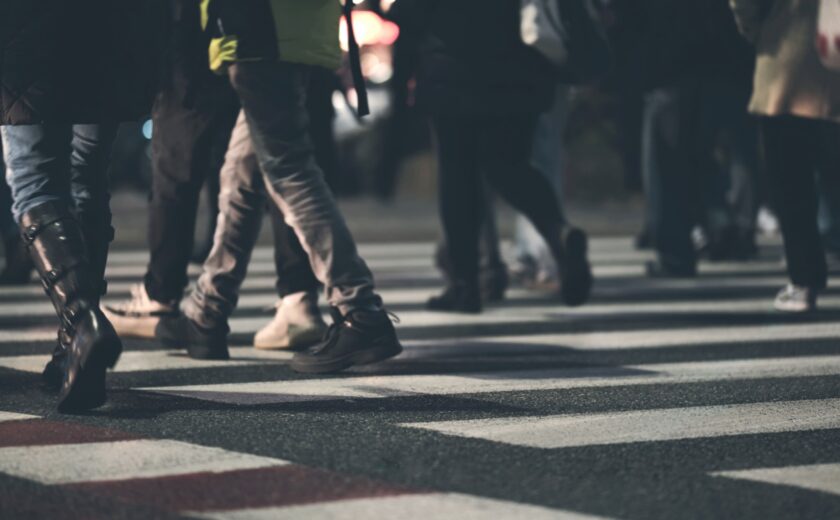 Various people crossing a zebra crossing at night