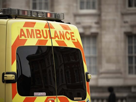 Rear of a yellow ambulance with orange chevrons and 'AMBULANCE' text