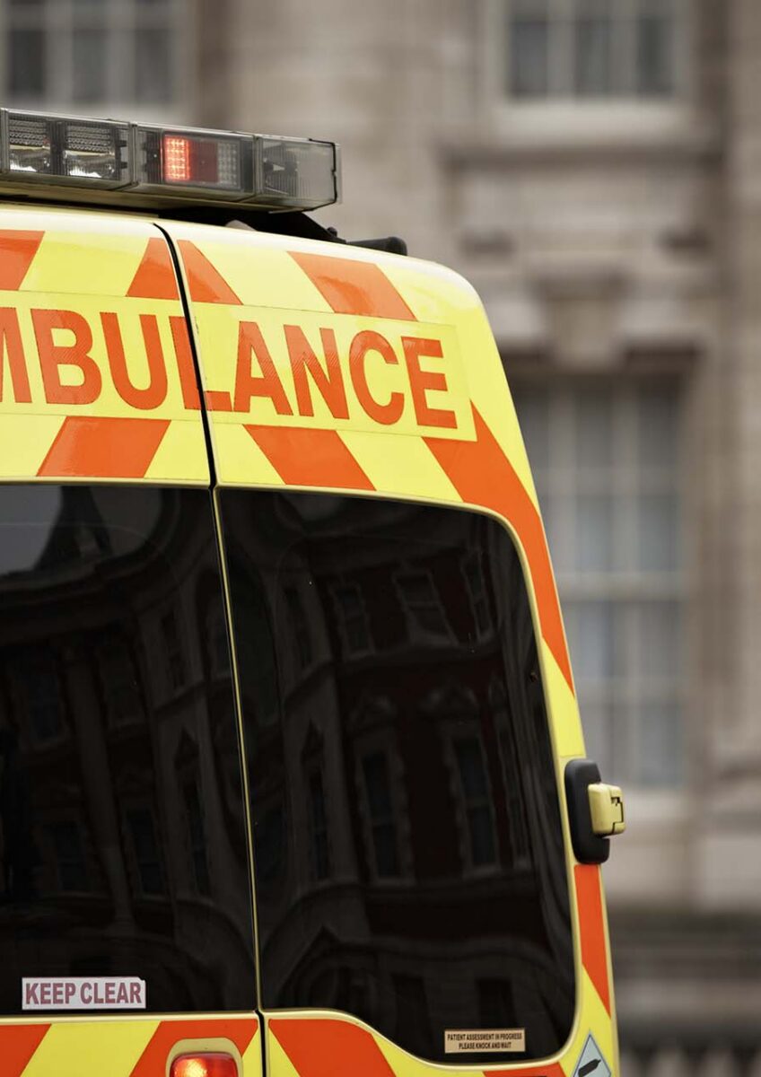 Rear of a yellow ambulance with orange chevrons and 'AMBULANCE' text
