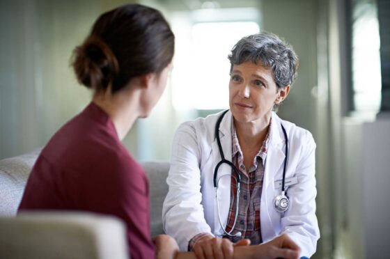 Doctor with stethoscope talking to woman in a consultation room