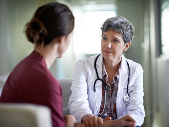 Doctor with stethoscope talking to woman in a consultation room