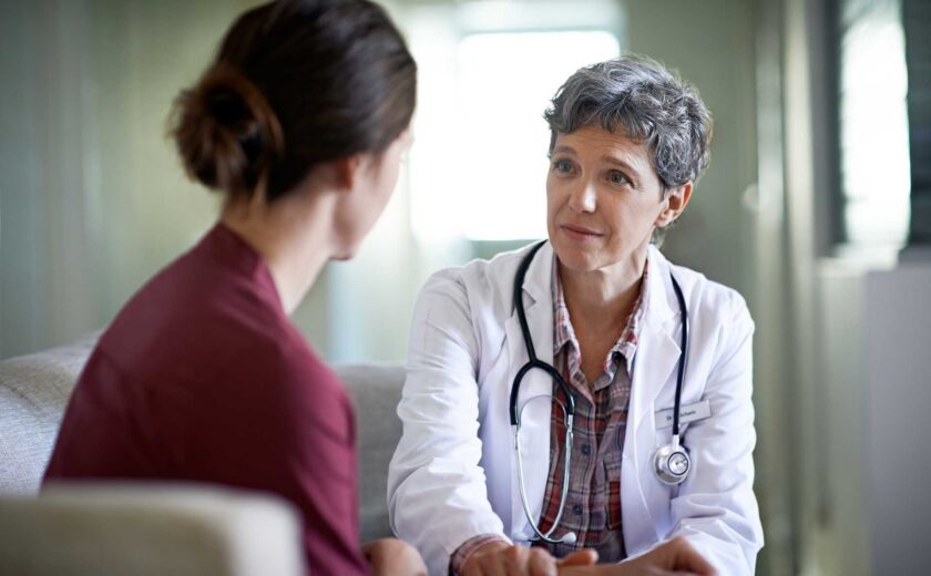 Doctor with stethoscope talking to woman in a consultation room