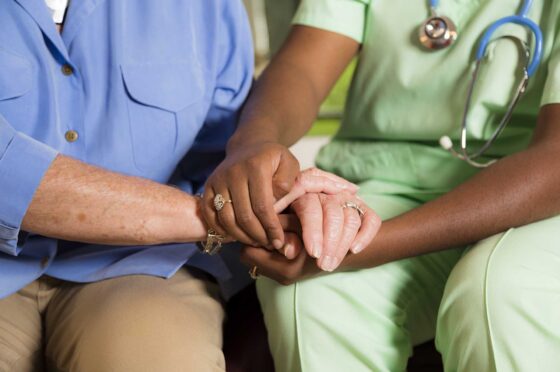Medical professional holding hands with an elderly person for comfort