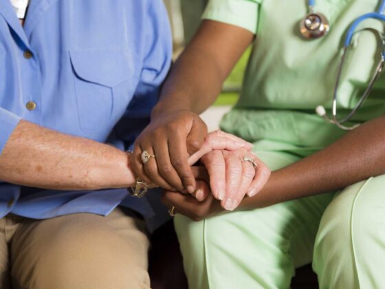 Medical professional holding hands with an elderly person for comfort