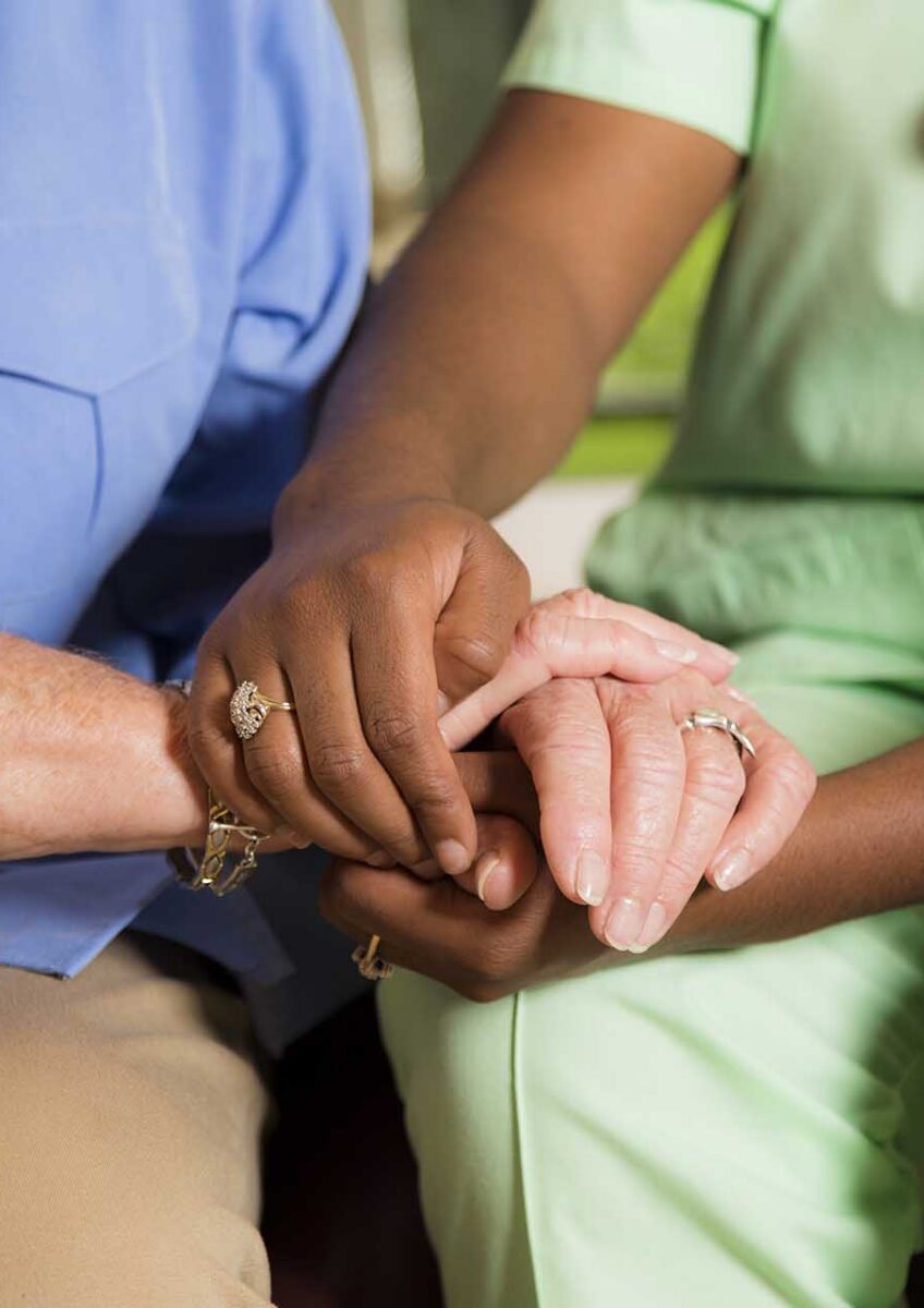 Medical professional holding hands with an elderly person for comfort