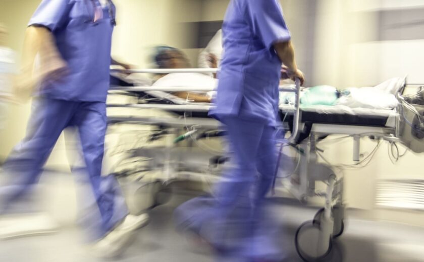 Blurred hospital corridor with medical staff pushing patient on trolley