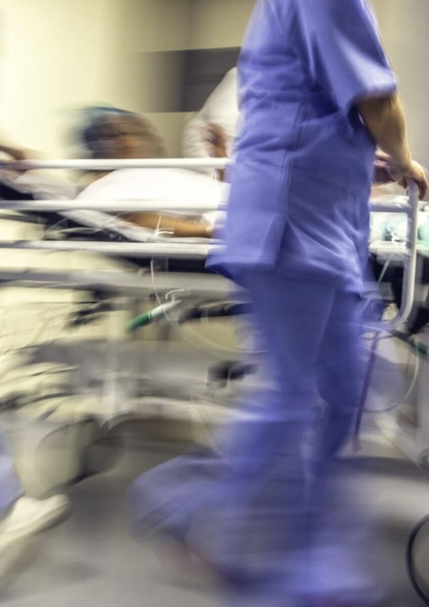 Blurred hospital corridor with medical staff pushing patient on trolley
