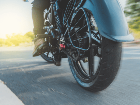 Close-up of motorcycle rear wheel and chain with rider on road