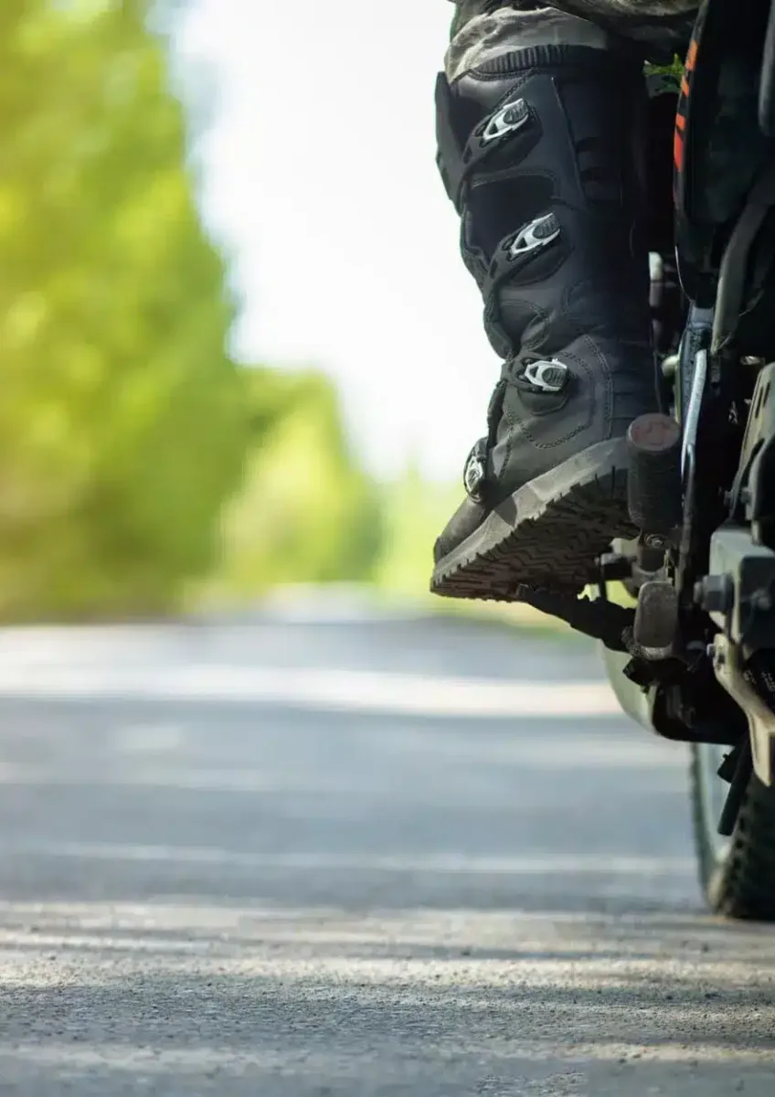 Motorcyclist's boot on footpeg of motorcycle on rural road