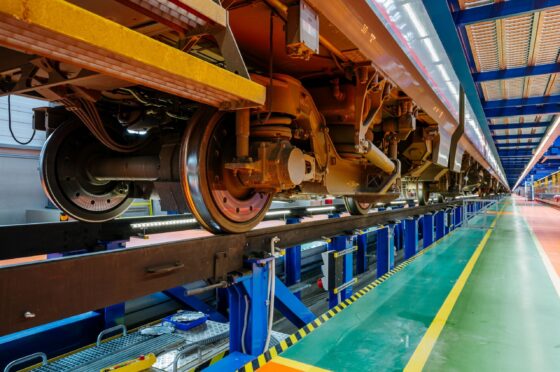 Close-up underside view of train wheels on tracks inside maintenance depot
