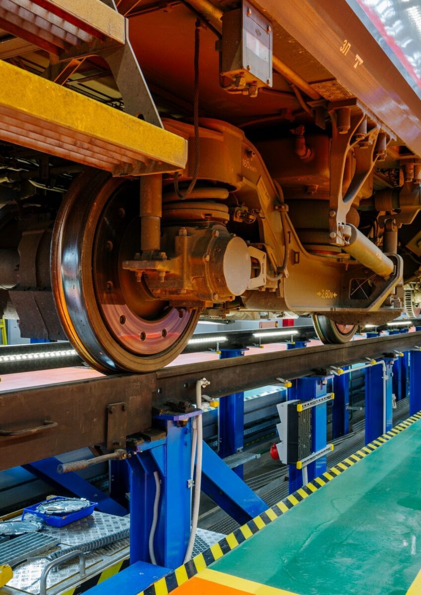 Close-up underside view of train wheels on tracks inside maintenance depot