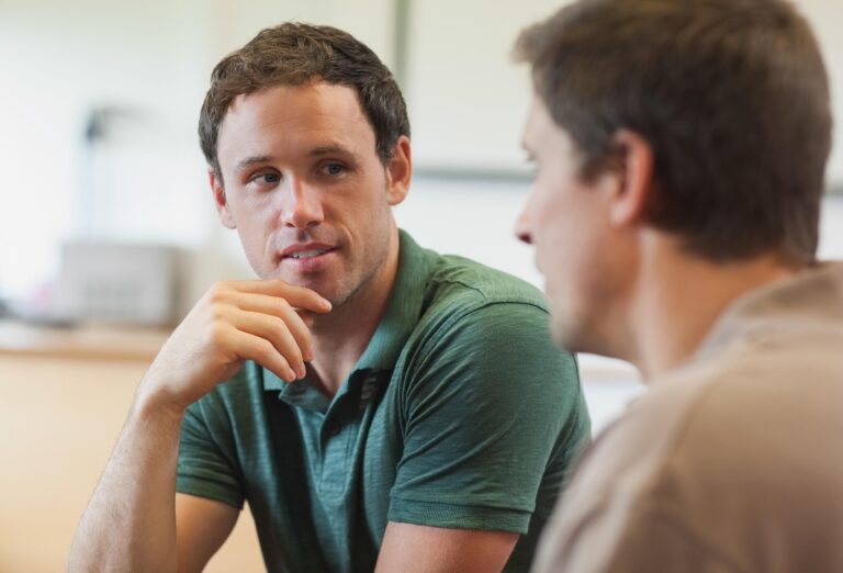 Two men having a conversation sitting in class room